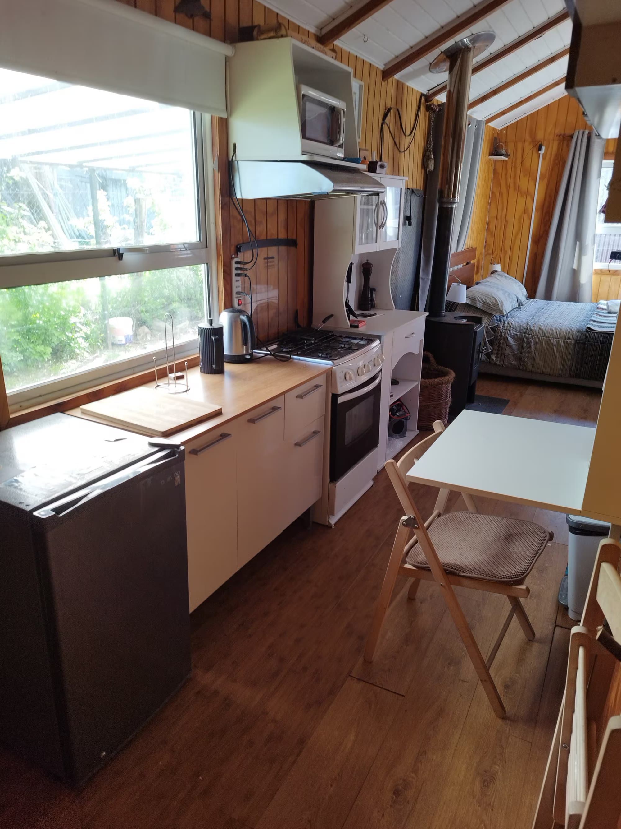 El mesón de la cocina con hervidor, horno y una mesa plegable junto a la ventana