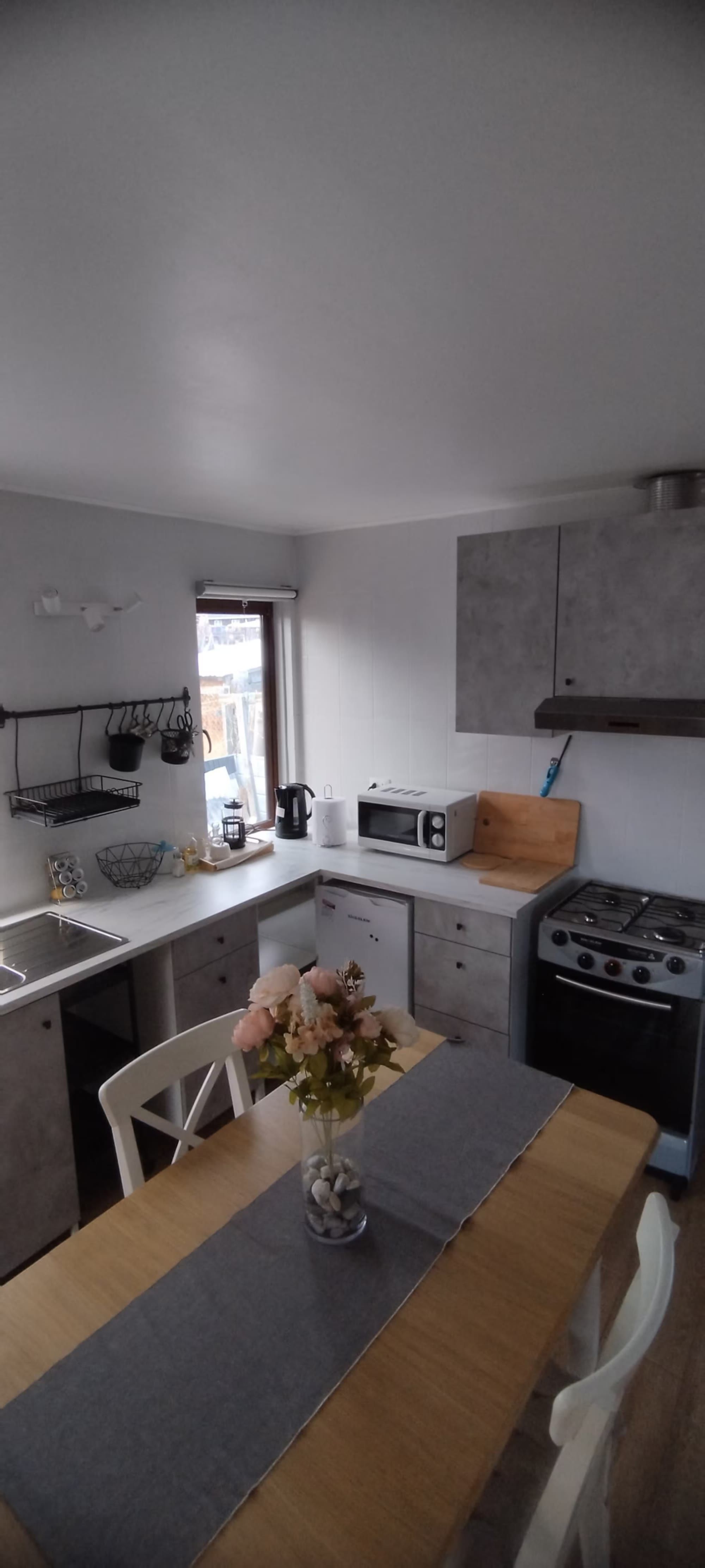 La cocina con mesón en L, microondas, refrigerador y cocina a gas